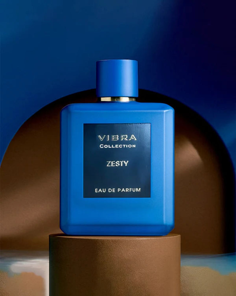 Blue perfume bottle labeled 'Zesty' by Vibra Collection on a brown platform with a blue background