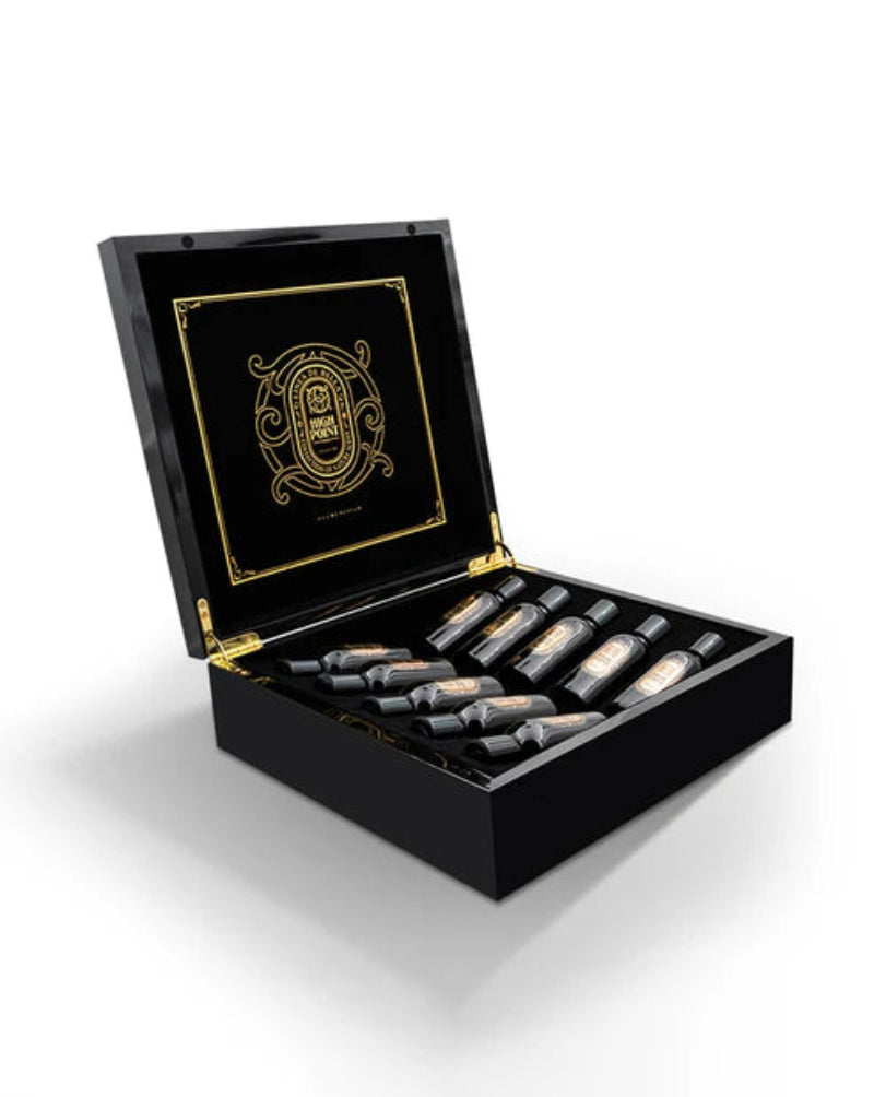 Black jewelry box with gold accents containing small bottles, likely perfume or cologne, on a white background.