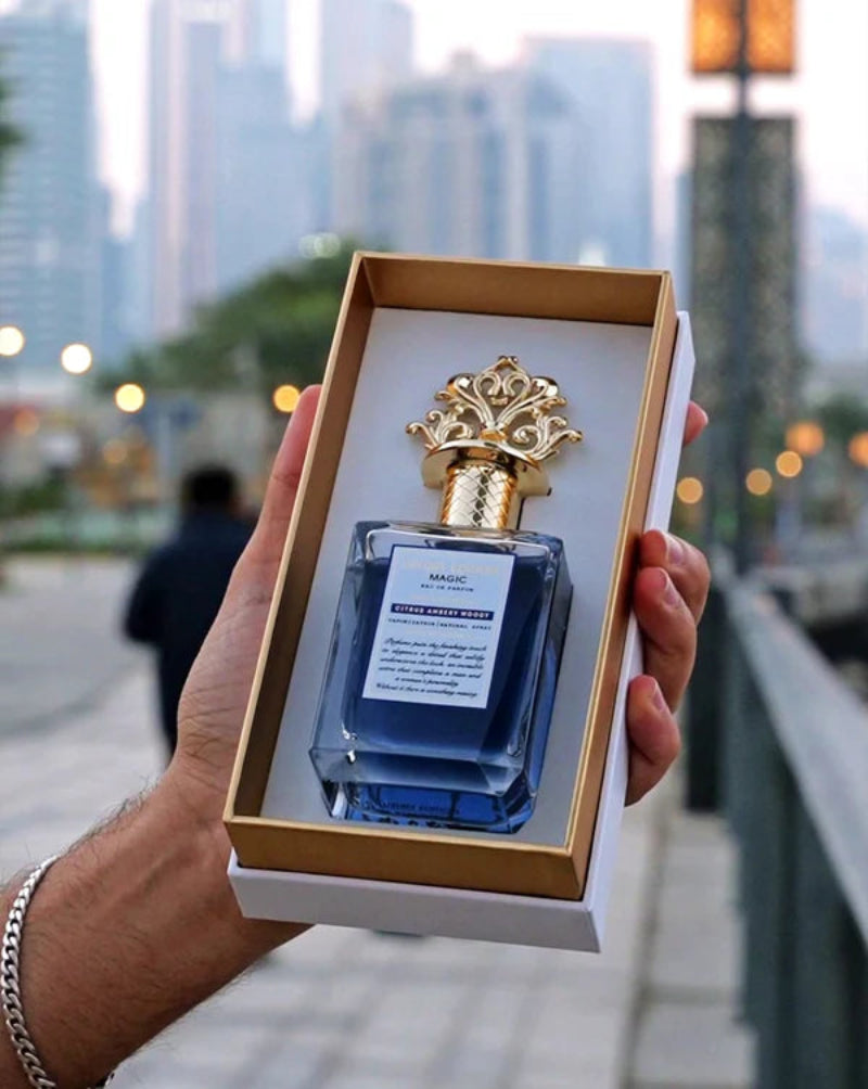 Blue perfume bottle with gold cap in a box held against a cityscape background